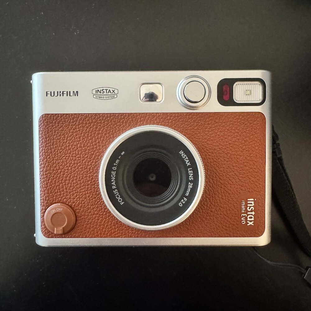 Fujifilm Instax mini Evo with lens cap, camera strap, and x16 film